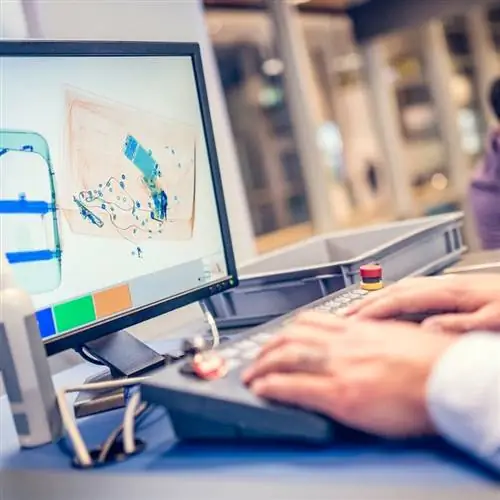 Сотрудники службы безопасности проверяют сумку через экран детектора в аэропорту