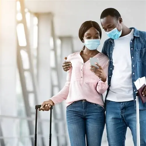 Счастливая пара путешественников, проверяющая свои телефоны в аэропорту