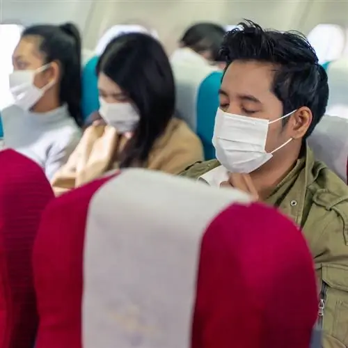 Путешественники носят маску для предотвращения заражения Covid-19 во время полета