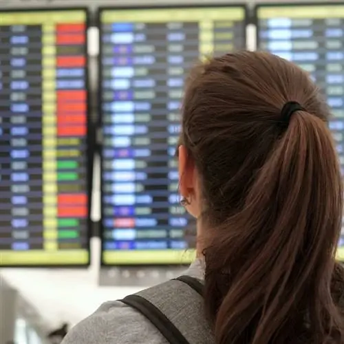 Женщина смотрит на расписание вылетов в аэропорту