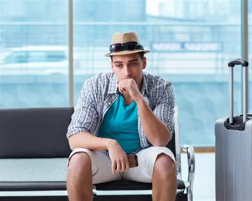 Молодой путешественник в летней одежде и задумчиво смотрит в зал ожидания аэропорта