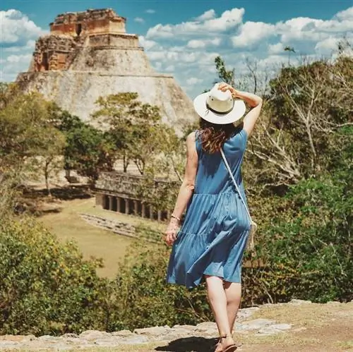 турист сзади стоит на руинах с видом на руины майя в Мексике, солнечный день