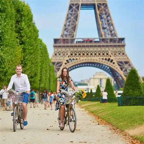 Пара на велосипедах возле Эйфелевой башни в Париже