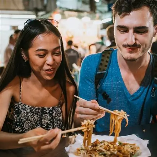 Молодая пара вместе ужинает на уличном рынке в Бангкоке, Таиланд