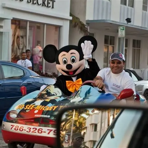 Счастливый посетитель парков Disney World, катающийся с персонажем Микки Мауса, Орландо, Флорида