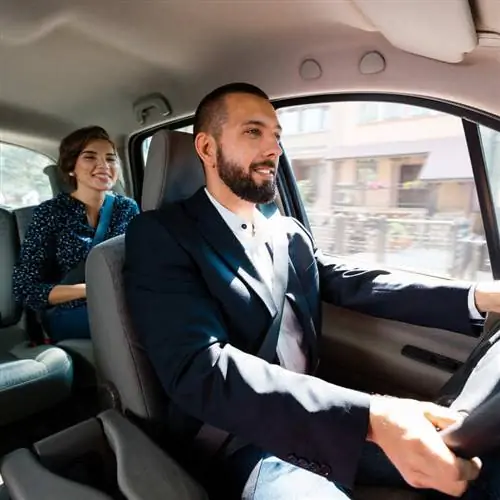 Улыбающийся таксист Uber везёт пассажирку к месту назначения Улыбающийся таксист Uber везёт пассажирку к месту назначения