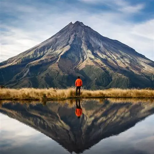Мужчина смотрит на гору в Новой Зеландии с озером на переднем плане