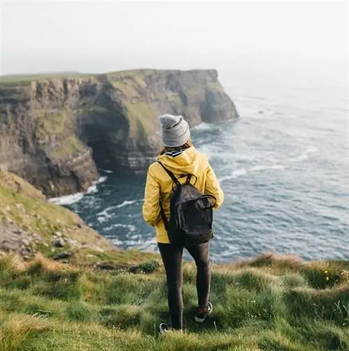 Скалы Мохера Турист стоит на краю скалы