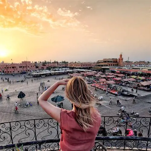 Женщина-туристка фотографирует рынок Джамаа Эльфна в Марракеше, Марокко