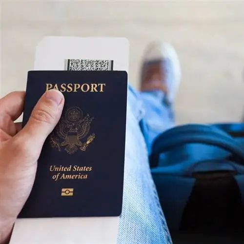 Молодой путешественник-мужчина держит паспорт США и посадочный талон в аэропорту