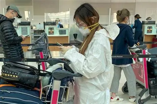 Пассажиры в масках регистрируются на рейс в аэропорту Торонто Пирсон, Канада