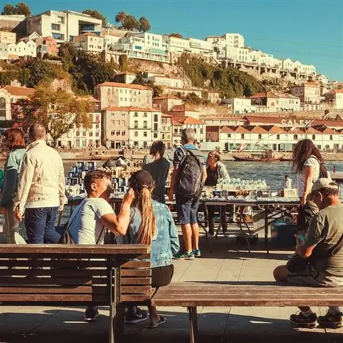 Многие люди гуляют по историческому берегу реки Дору, солнечный день