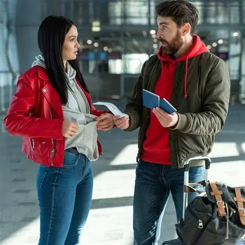 Молодая пара путешественников, похоже, спорит друг с другом, держа в руках паспорта и посадочные талоны перед международным путешествием