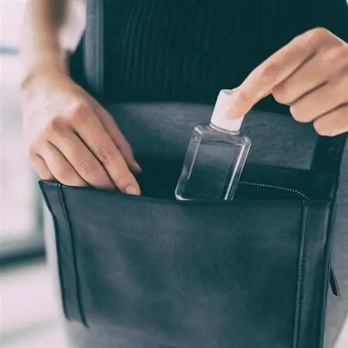 Путешественник упаковывает дезинфицирующее средство для рук в небольшую сумочку