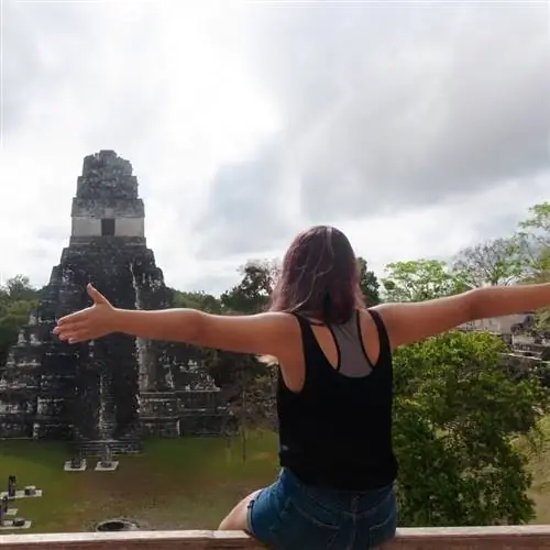 Молодая путешественница раскрывает объятия, чтобы сфотографироваться перед археологическим памятником майя в Гватемале, Центральная Америка