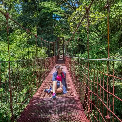 Молодая туристка сидела посреди подвесного моста в джунглях Коста-Рики, Центральная Америка