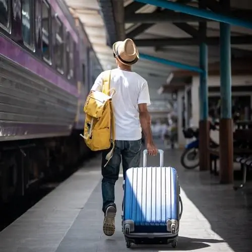 Мужчина-путешественник в летней одежде направляется к поезду, концепция путешествия на поезде