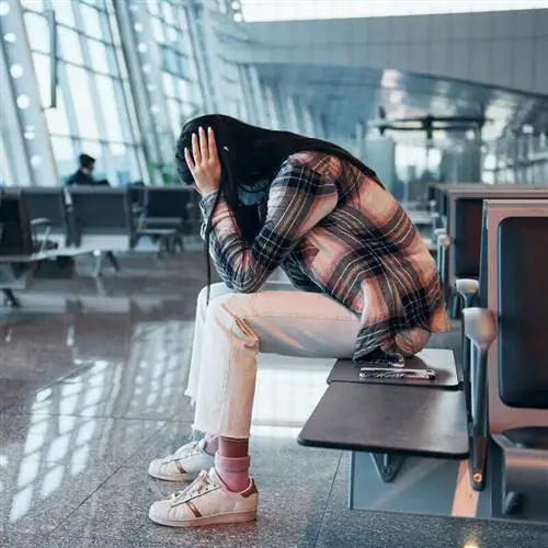 Женщина-путешественница выглядит расстроенной, расстроенной, плачет, держа голову руками в аэропорту, концепция сбоя рейса