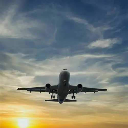 Неопознанный самолет, летящий на фоне заката, концепция международного путешествия