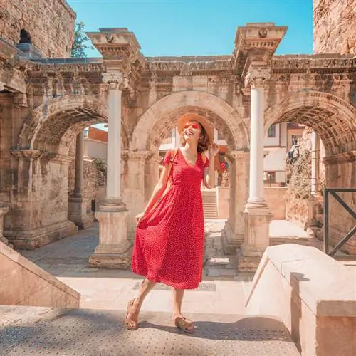 Молодая счастливая туристка позирует у ворот Адриана в Анталье, Турция