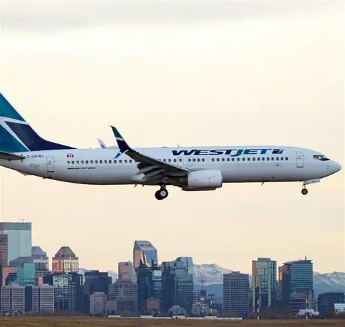 Самолет Westjet пролетает над горизонтом Калгари на заднем плане