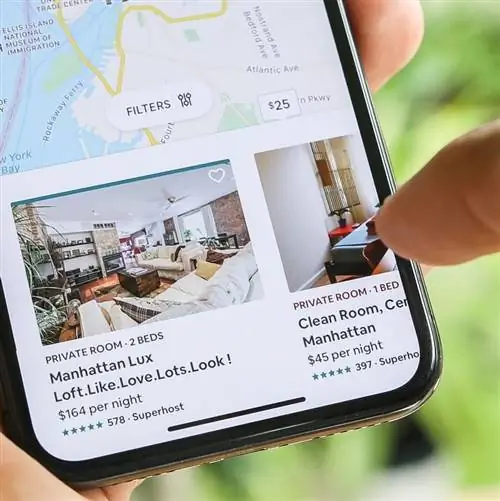 Мужчина держит телефон и смотрит на объявление Airbnb в Нью-Йорке
