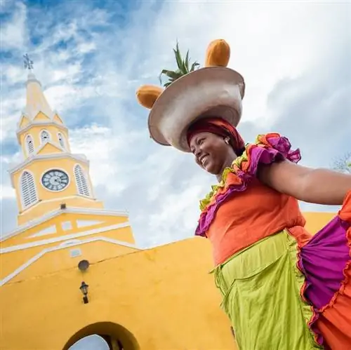 Счастливый Паленкера продает фрукты в Картахене на фоне желтого колониального здания