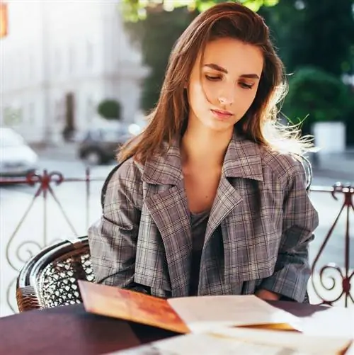 Молодая женщина смотрит меню ресторана после поездки в Европу