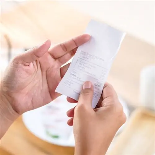 Женщина смотрит на чек за едой