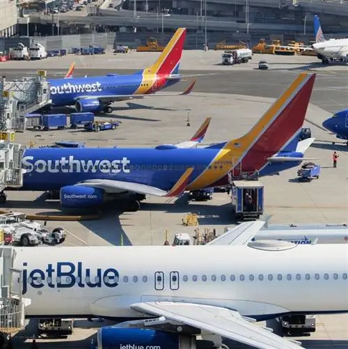 Самолеты Jetblue и Southwest рядом друг с другом в терминале аэропорта перед вылетом рейсов