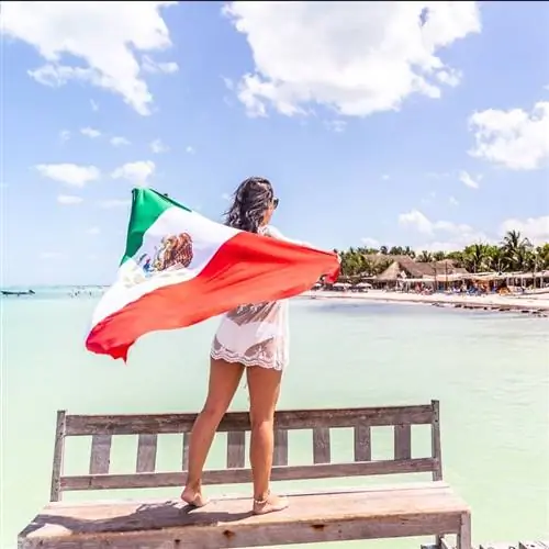 Молодая туристка под мексиканским флагом смотрит на океан