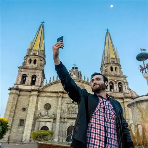 Молодой турист делает селфи перед собором Гвадалахары, Мексика