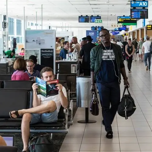 Оживленный аэропорт, где пассажиры транзитом, читают или ждут вылета самолета, концепция международных путешествий