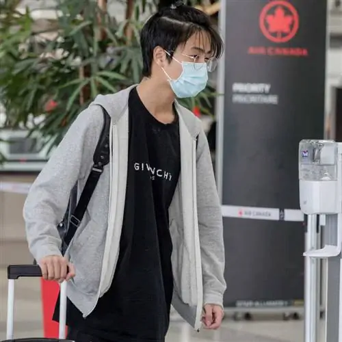 Молодой путешественник-мужчина прибывает в международный аэропорт Торонто Пирсон с размытым на заднем плане знаком Air Canda, Торонто, Канада