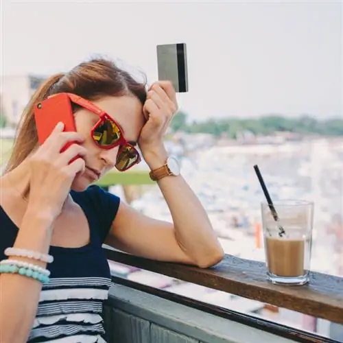 Концепция мошенничества в путешествиях. Изображение женщины, держащей кредитную карту во время разговора по телефону с видом на море