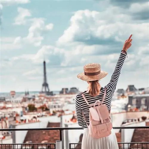 Молодая путешественница, стоящая на крыше в Париже с видом на Эйфелеву башню
