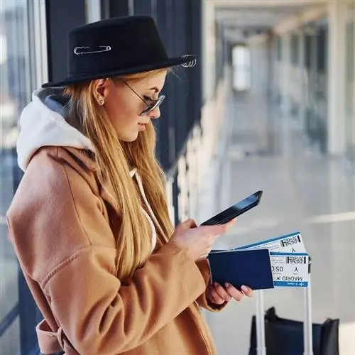 Молодая путешественница проверяет свой телефон в аэропорту