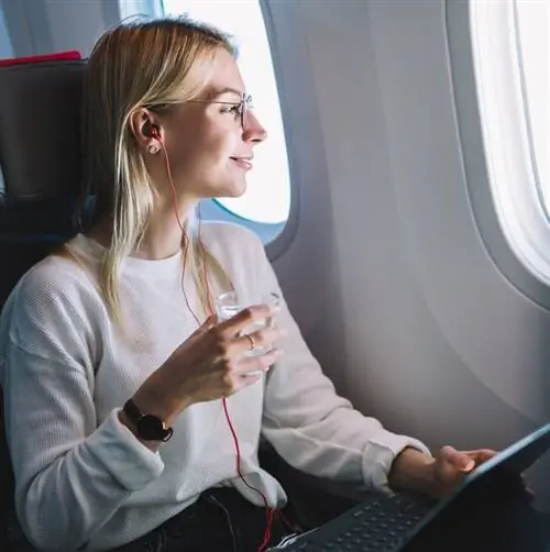 Женщина наслаждается пребыванием в самолете, глядя в окно