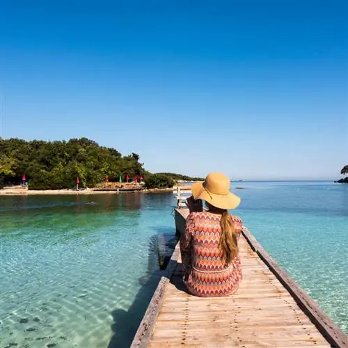 Молодая путешественница, сидящая на океанском пирсе на Албанской Ривьере, Албания