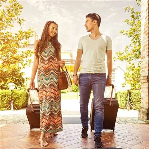 Молодая пара идет с чемоданами в отель