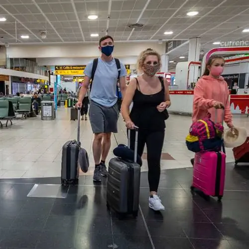 Авиапутешественники в масках во время транзита через аэропорт, концепция воздушного путешествия