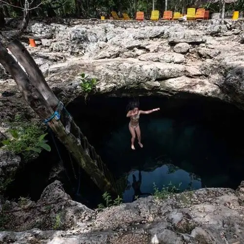 Молодая туристка прыгает в сенот Кальвера, Мексика