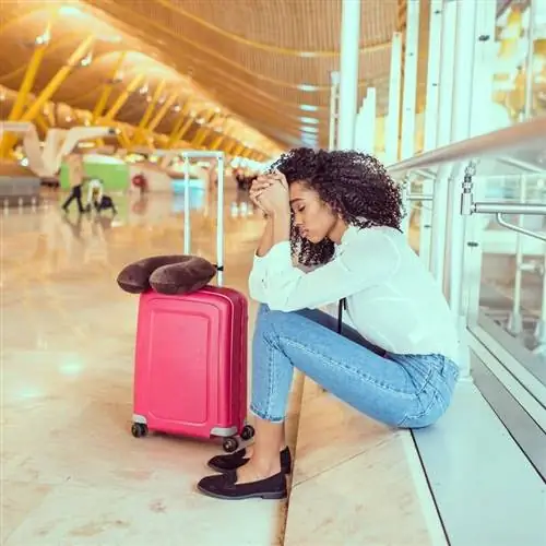 Молодая путешественница выглядит расстроенной и грустной в аэропорту после отмены или задержки рейса