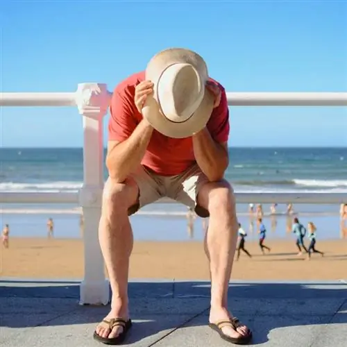 Грустный отчаявшийся мужчина на набережной, концептуальное изображение на пляже