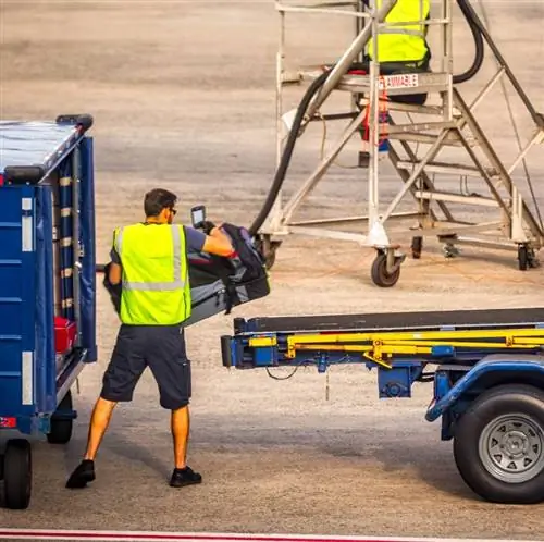 Обработчик багажа загружает сумку на конвейер для самолета