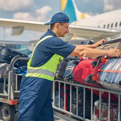 Персонал аэропорта, обработчик багажа обрабатывают сумки во время их выгрузки из самолета