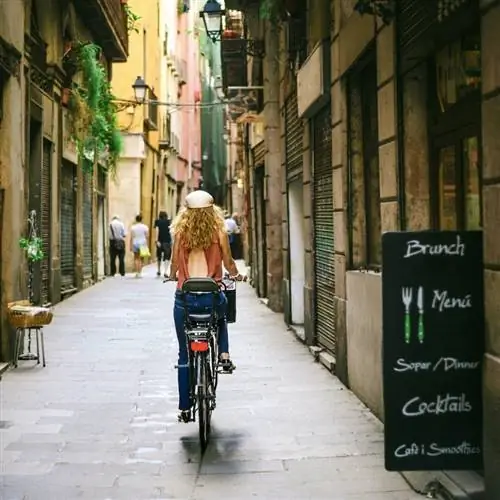 Женщина едет на велосипеде по старой улице Барселоны
