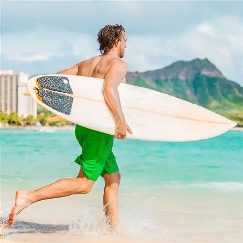 Серфер бежит в океан с доской для серфинга на Гавайях, США