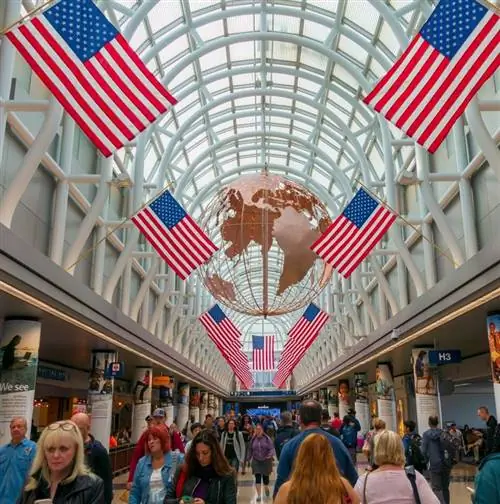 Люди, идущие в аэропорту Чикаго ORD O'Hare под американскими флагами. Соединенные Штаты