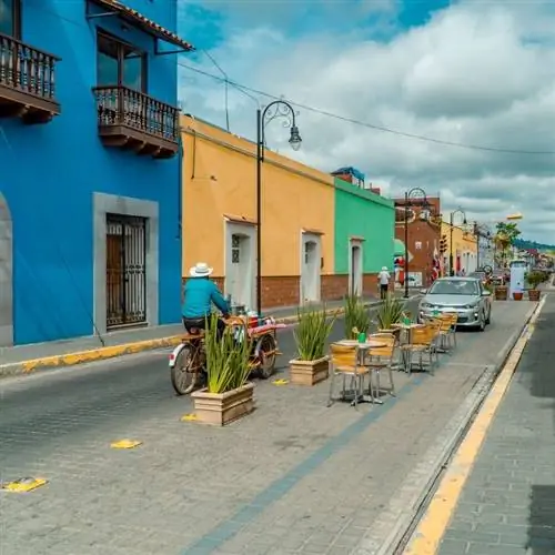Мужчина едет на велосипеде по красочной улице в Чолуле, Пуэбло Мэджико в Мексике